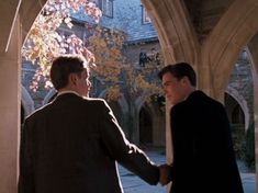 two men shaking hands in front of an archway