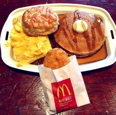 a white tray topped with pancakes and other breakfast foods on top of a wooden table