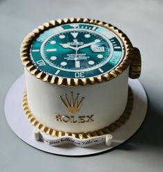 a white and gold cake with a blue rolex watch on it