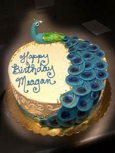 a birthday cake decorated with blue and green peacock feathers