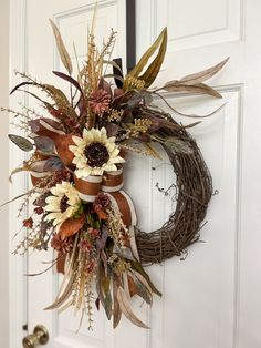 a wreath with dried flowers and leaves hanging on the front door to give it an autumn feel