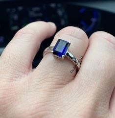 a person's hand with a ring on it and a blue stone in the middle