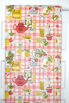 a pink and white checkered table cloth with various kitchen items on it