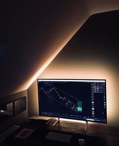 a computer monitor sitting on top of a desk under a slanted ceiling in a dimly lit room