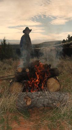 a man standing next to a fire in a field