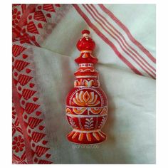 a red and white vase sitting on top of a bed next to a striped blanket