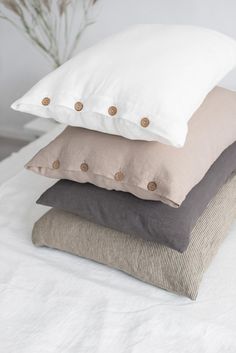 four pillows stacked on top of each other in different colors and sizes, all with buttons