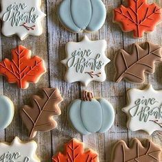 decorated cookies are arranged on a wooden table with leaves and acorns in different colors