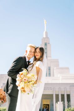 a bride and groom pose in front of the stately building