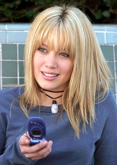 a woman with blonde hair holding a cell phone