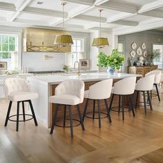 a kitchen with an island and bar stools in the center, surrounded by wooden floors