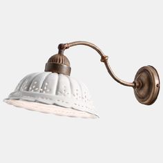 an old fashioned wall light with a white shade on the side and a brown arm