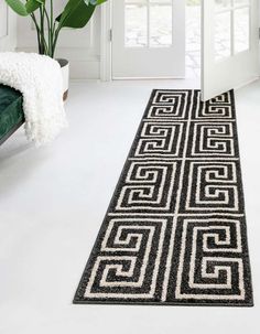 a black and white runner rug on the floor in front of a door with potted plant