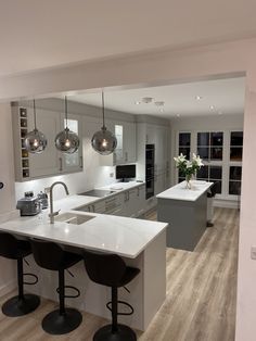 a large kitchen with an island and bar stools next to it, in the middle of a living room