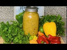 a jar filled with green liquid surrounded by vegetables