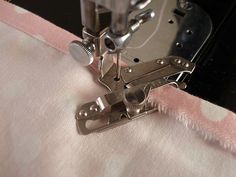 the sewing machine is working on the pink and white material that has been sewn