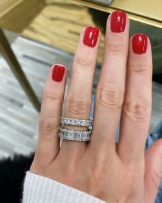 a woman's hand with two wedding bands on it and a red manicure