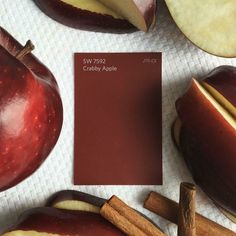 an apple with some cinnamon sticks next to it and a red color swatch on the side