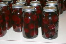 many jars filled with red pickles sitting on a table