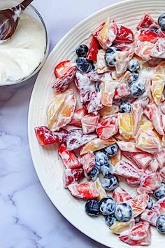 a white plate topped with fruit salad next to a bowl of yogurt