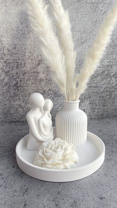 a white vase sitting on top of a table next to a feather in it's mouth