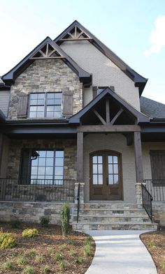 a large house with stone and wood trimmings on the front door, stairs leading up to it