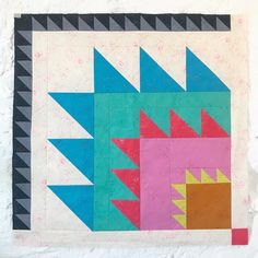 a colorful quilt on a white surface with black and pink squares in the center,