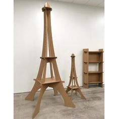 three wooden sculptures in the shape of eiffel tower and bookshelves on display