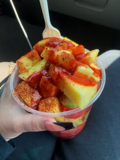 a person holding a plastic container filled with food and sauces on top of it