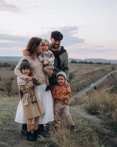 a man, woman and two children are standing on a path in the middle of a field