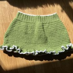 a green crocheted skirt sitting on top of a wooden floor