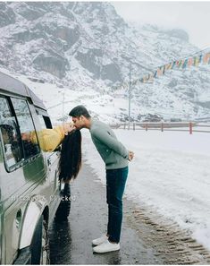 a man kissing a woman in front of a car on the side of a road