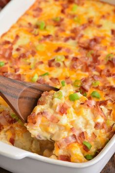 a casserole dish with ham and green onions in it being scooped from the casserole