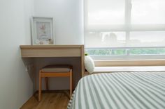 a bed room with a neatly made bed and a desk next to it on top of a hard wood floor