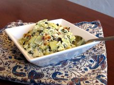 a white bowl filled with food sitting on top of a blue and white table cloth