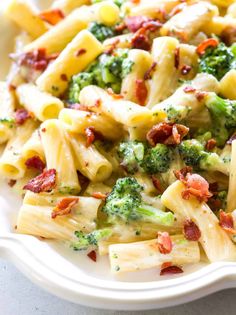 a pasta dish with broccoli, bacon and cheese in it on a white plate