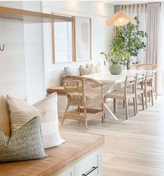 a living room with white walls and wooden flooring next to a dining table surrounded by chairs