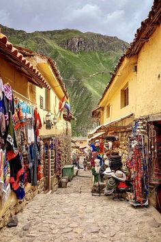 an alley way with shops and clothes hanging on the walls, mountains in the background