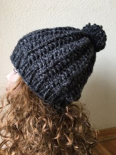 a woman with curly hair wearing a crocheted hat