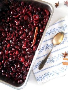 a pan filled with cranberry sauce next to cinnamon sticks and anisette