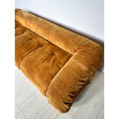 a brown couch sitting on top of a hard wood floor next to a white wall