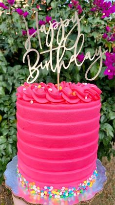 a pink birthday cake with sprinkles and a happy birthday sign on top