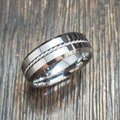 a silver ring with braiding on it sitting on top of a wooden table