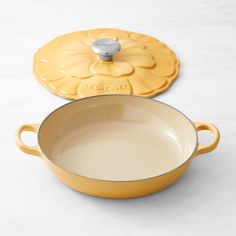 a yellow pot with lid sitting on top of a white counter next to an empty pan