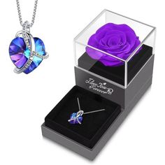 a purple rose in a glass box next to a necklace and pendant with swarong crystals