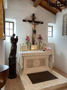 the interior of a church with a crucifix and flowers on the alter