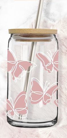 a glass jar filled with pink butterflies and a straw