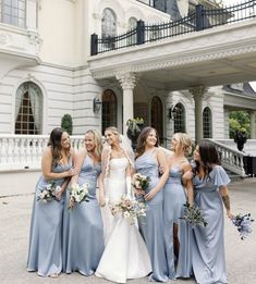 a group of women standing next to each other in front of a large white building