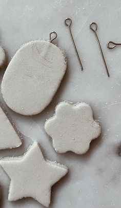 some white cookies are sitting on a table with pins and needles next to them,