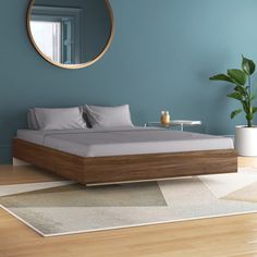 a bed sitting on top of a hard wood floor next to a mirror and potted plant